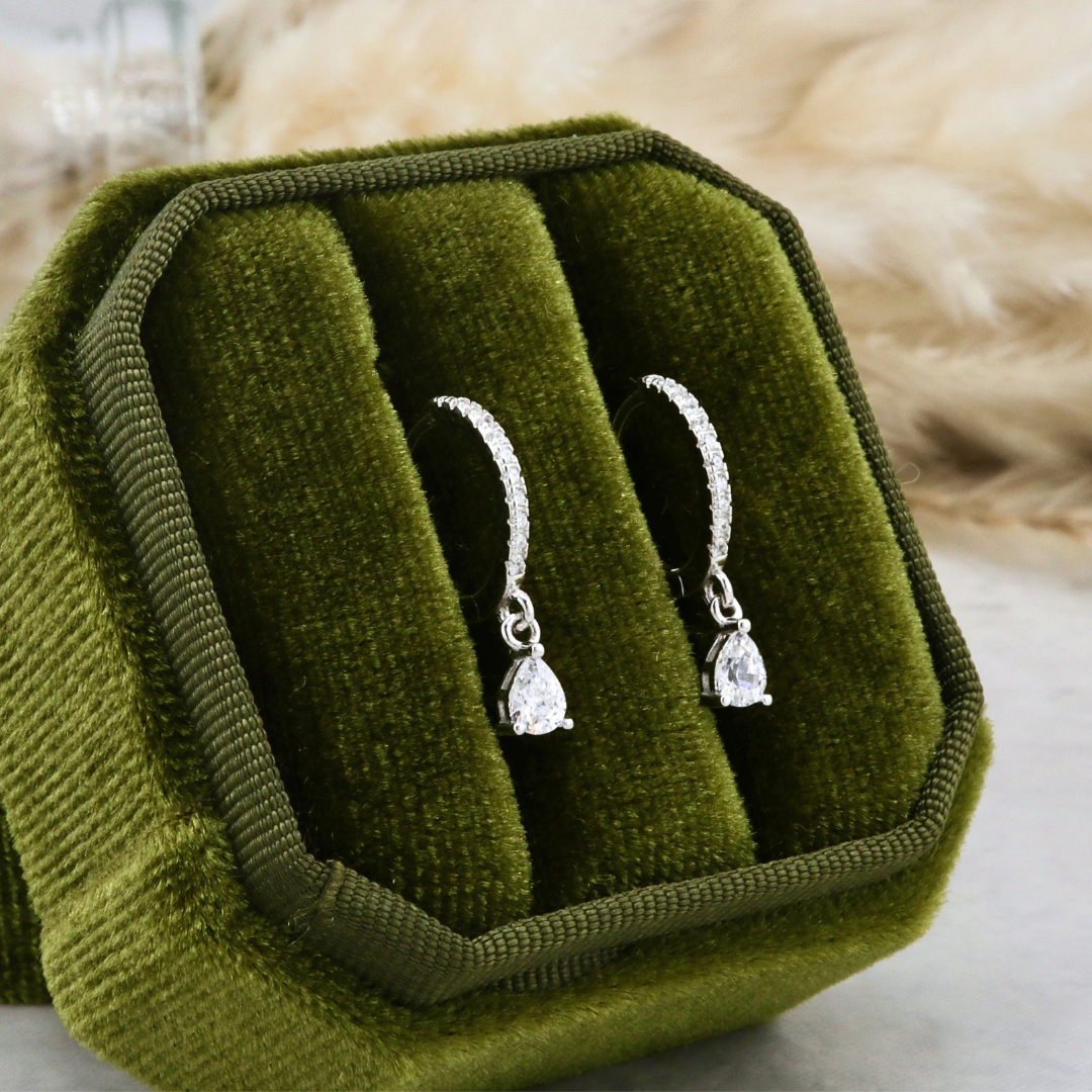 Boucles d’oreilles Huggies gouttes en argent, présentées dans un écrin velours vert